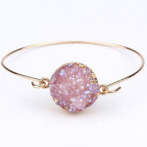 Pale lilac druzy quartz cuff bracelet with its gold-tone hook fastening open beside the circular stone face.