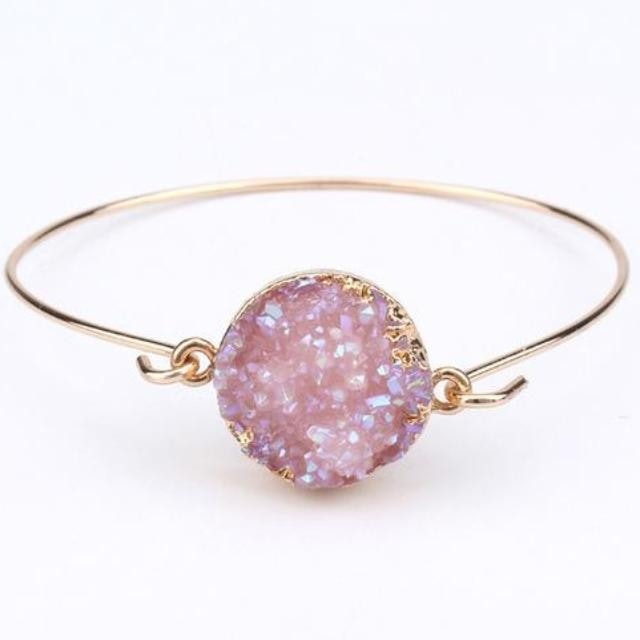 Pale lilac druzy quartz cuff bracelet with its gold-tone hook fastening open beside the circular stone face.