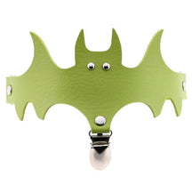 Lime green bat-shaped leg garter with small metallic eye details and a central hanging clip.