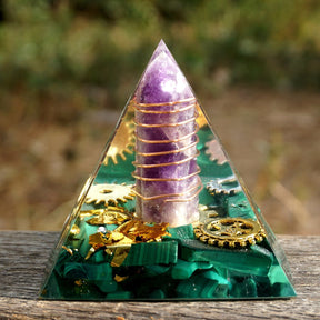Full view of the malachite pyramid standing on a wooden surface, with the wrapped purple point facing forward.