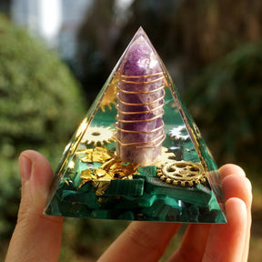 Malachite and amethyst orgone pyramid held in a hand, showing the complete clear outline around the wrapped purple point.