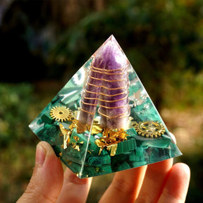 The amethyst point and its spiral wrapping are visible from the side of the clear pyramid above a green malachite layer.