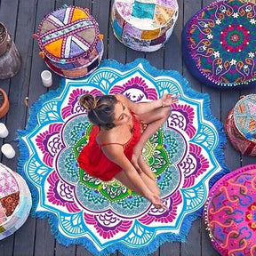 Blue and pink mandala flower throw seen from above beneath a woman in a red swimsuit, with patterned cushions beside the circular floral design.