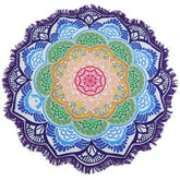 Purple-edged mandala flower throw with green, yellow and blue petal rings around a pink centre, laid flat with white fringe visible.