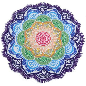Purple-edged mandala flower throw with green, yellow and blue petal rings around a pink centre, laid flat with white fringe visible.