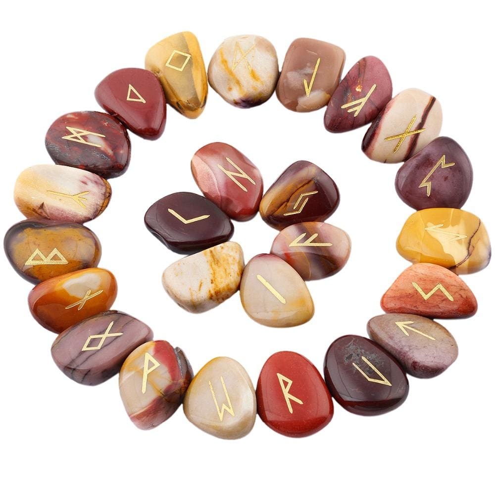 Mookaite rune stones arranged in a circle, with mustard, red and beige polished surfaces and gold-coloured characters. The set includes a blank stone.