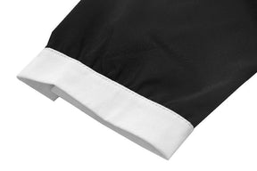 Close view of the black Moon Child blouse sleeve laid flat, showing the white cuff band and its stitched edge.