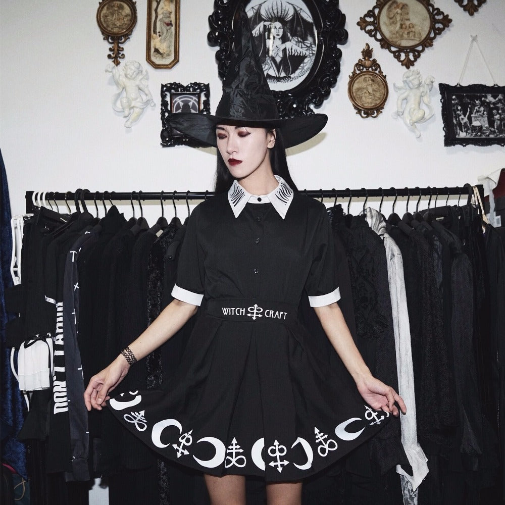 Moon Child blouse worn with a separate black skirt and wide-brim hat in a room with framed wall art and a clothing rail. The white collar and cuffs stand out against the dark outfit.