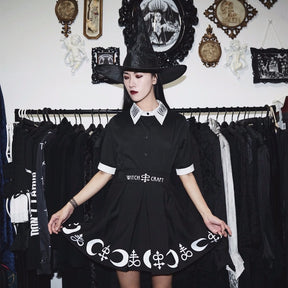 Moon Child blouse worn with a separate black skirt and wide-brim hat in a room with framed wall art and a clothing rail. The white collar and cuffs stand out against the dark outfit.