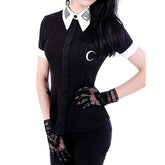 Close front view of the black button-up Moon Child blouse, showing white collar lettering, white cuffs and a crescent moon on the chest pocket, styled with separate lace gloves.