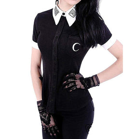 Close front view of the black button-up Moon Child blouse, showing white collar lettering, white cuffs and a crescent moon on the chest pocket, styled with separate lace gloves.