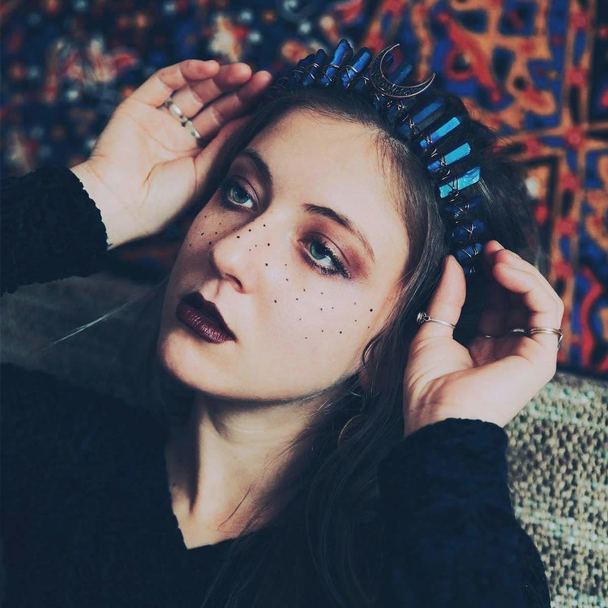 Blue crystal moon crown worn with dark hair and celestial makeup.
