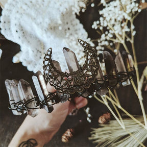 Handheld close view of the smoky quartz crescent crown beside pale dried flowers.