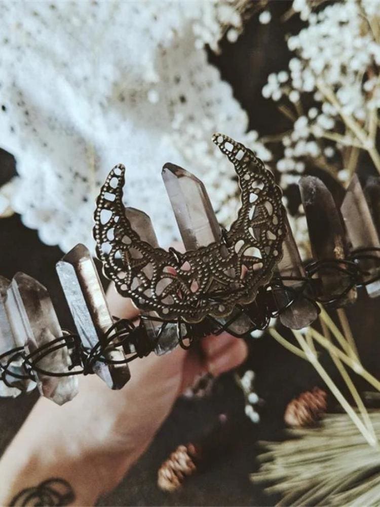 Smoky crystal moon crown displayed beside pale flowers, showing wire-wrapped points.