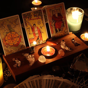 Wider candlelit arrangement around the brown wooden tarot stand, with three upright cards, a fanned deck and crystals across the tray.
