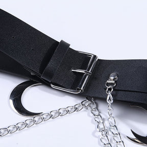 Detail of the black strap, rectangular pin buckle and belt keeper, with a silver-tone crescent and chain links arranged on the white surface below.