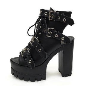 Side view of a black open-toe bootie with four broad buckle straps, an open heel area and a chunky platform sole.