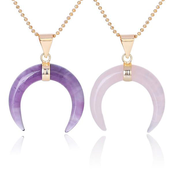 Purple amethyst and pale pink rose quartz crescent pendants displayed together, with downward-pointing tips and gold-tone chains.