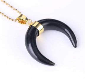 Black onyx crescent moon pendant with a gold-tone centre band and ball chain, shown against white.