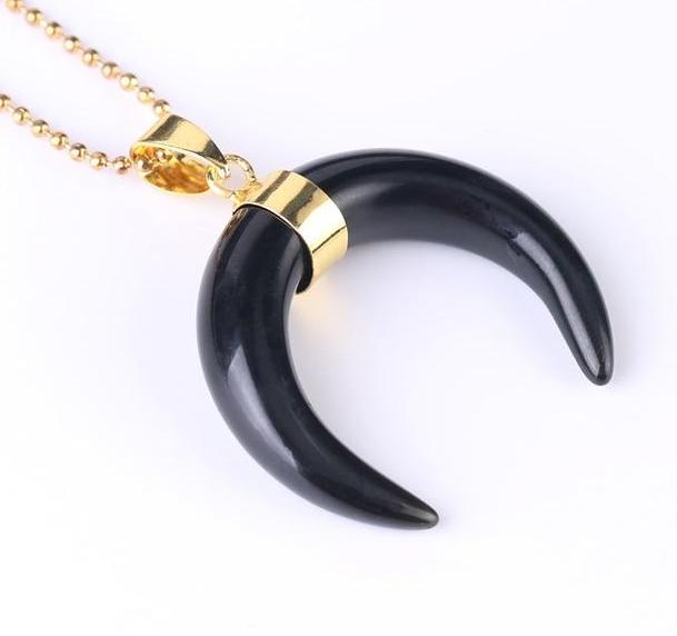 Black onyx crescent moon pendant with a gold-tone centre band and ball chain, shown against white.