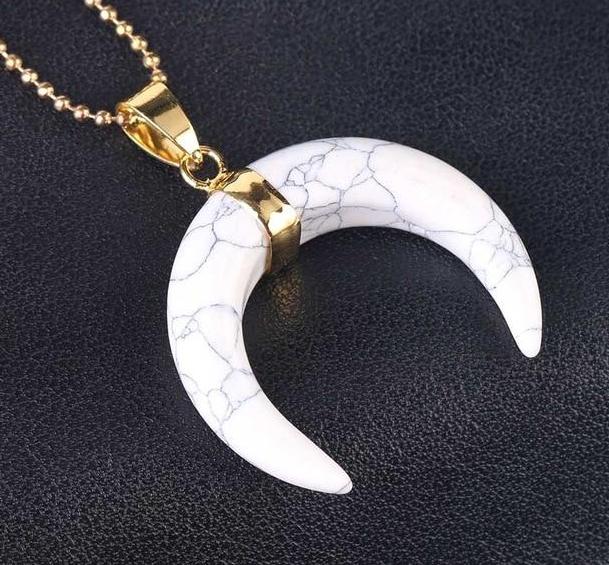 White howlite crescent moon pendant with dark veining across the polished face and a gold-tone centre band.