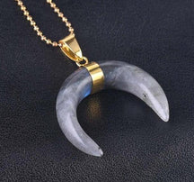 Grey labradorite crescent pendant with darker mottled areas, a gold-tone centre setting and chain.