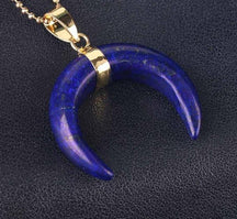 Deep blue lapis lazuli crescent pendant with scattered stone markings and a gold-tone ball chain.