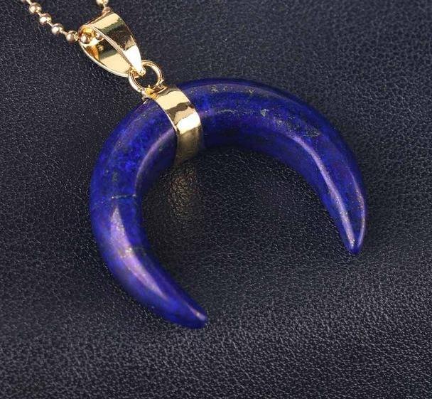 Deep blue lapis lazuli crescent pendant with scattered stone markings and a gold-tone ball chain.