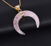 Pale pink rose quartz crescent pendant with polished downward tips and a gold-tone chain.