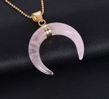 Pale pink rose quartz crescent pendant with polished downward tips and a gold-tone chain.