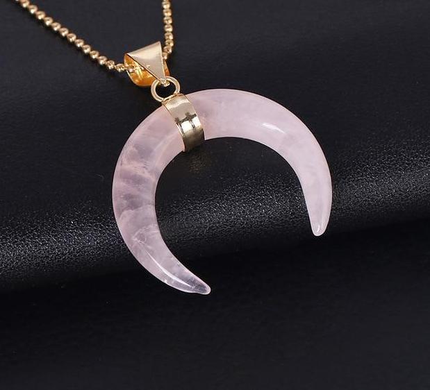 Pale pink rose quartz crescent pendant with polished downward tips and a gold-tone chain.