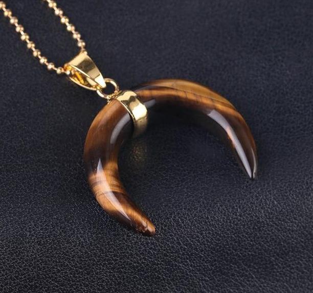 Brown tiger's eye crescent pendant with golden bands across its polished face and a gold-tone chain.