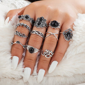 Eleven-piece silver-tone Namaste ring set with black accents worn across fingers with white nail polish.