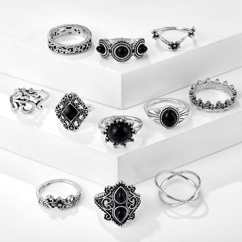 Eleven-piece silver-tone Namaste ring set with black accents shown in a second arrangement on stepped blocks.