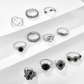 Eleven-piece silver-tone Namaste ring set with black accents spread across white display steps.