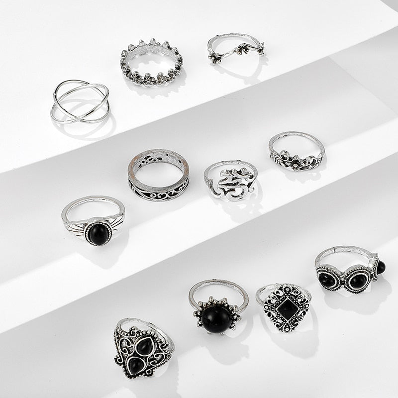 Eleven-piece silver-tone Namaste ring set with black accents spread across white display steps.