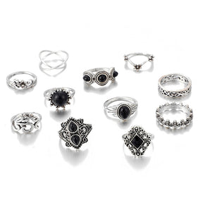 Eleven-piece silver-tone Namaste ring set with black accents arranged together on white with the Om motif and crossed band visible.