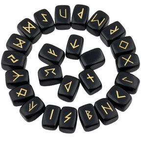 Obsidian rune stones arranged in a circle, with glossy black polished surfaces and gold-coloured characters. The set includes a blank stone.