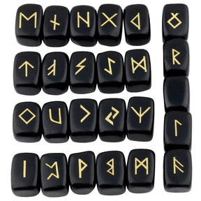 Obsidian rune stone set laid out in rows, showing individual gold-coloured characters and one unmarked stone against glossy black surfaces.