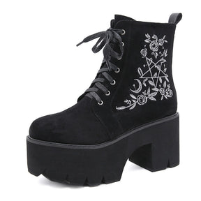 Black platform ankle boots with white pentagram, moon and rose embroidery shown from an angled front view.