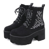 Black platform ankle boots with white pentagram, moon and rose embroidery shown as a pair at a three-quarter angle.