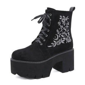 Black platform ankle boots with white pentagram, moon and rose embroidery shown as a single boot at a side angle.