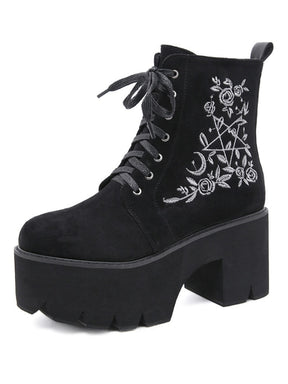 Black platform ankle boots with white pentagram, moon and rose embroidery shown as a single boot on white.