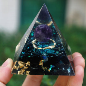 Ocean amethyst orgone pyramid with a purple sphere, blue flakes and dark obsidian stones. Shaded front view highlighting the dark stones and gold-tone flecks at the base.