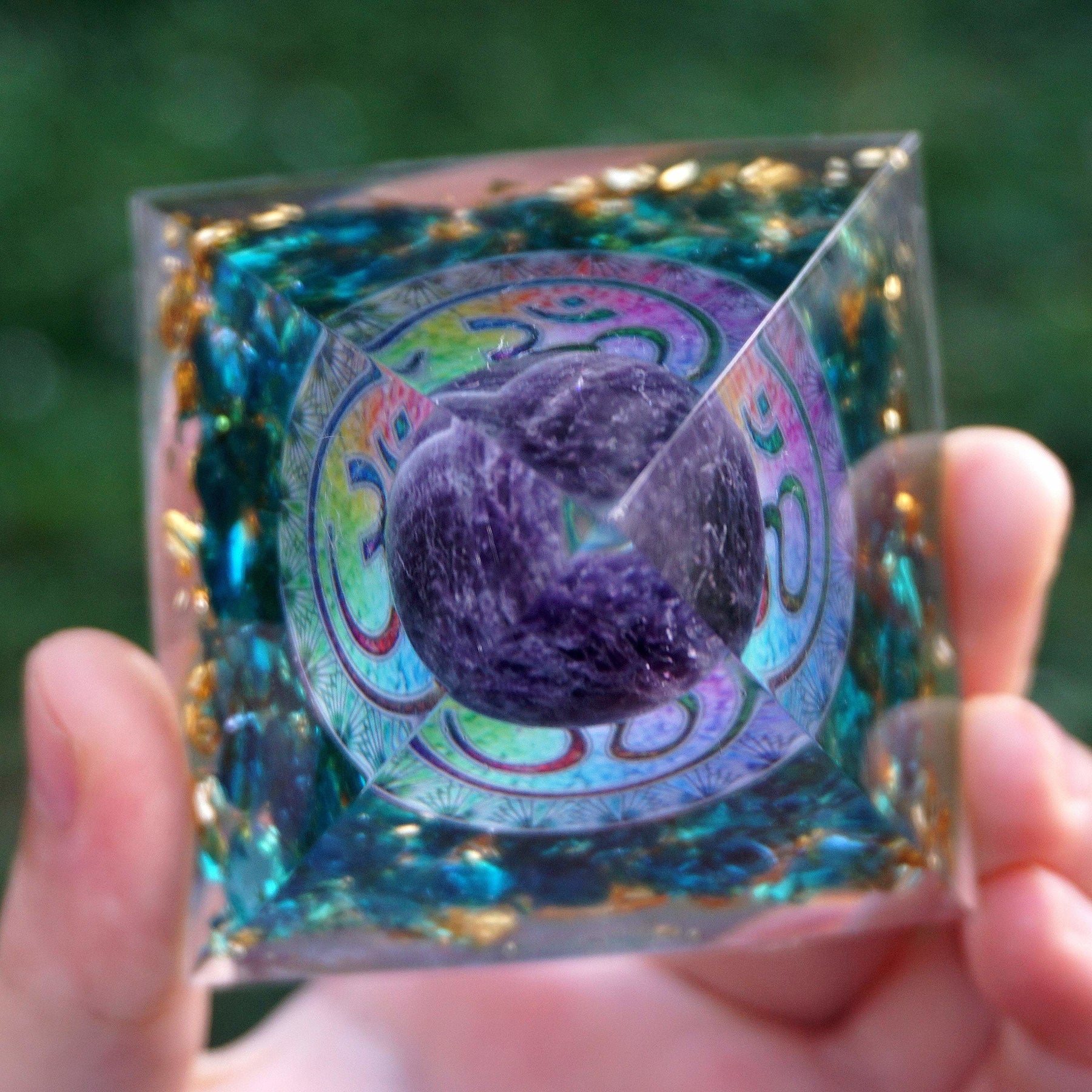 Top view of the Om orgone pyramid, with a purple amethyst sphere visible above the blue quartz and gold-tone details.