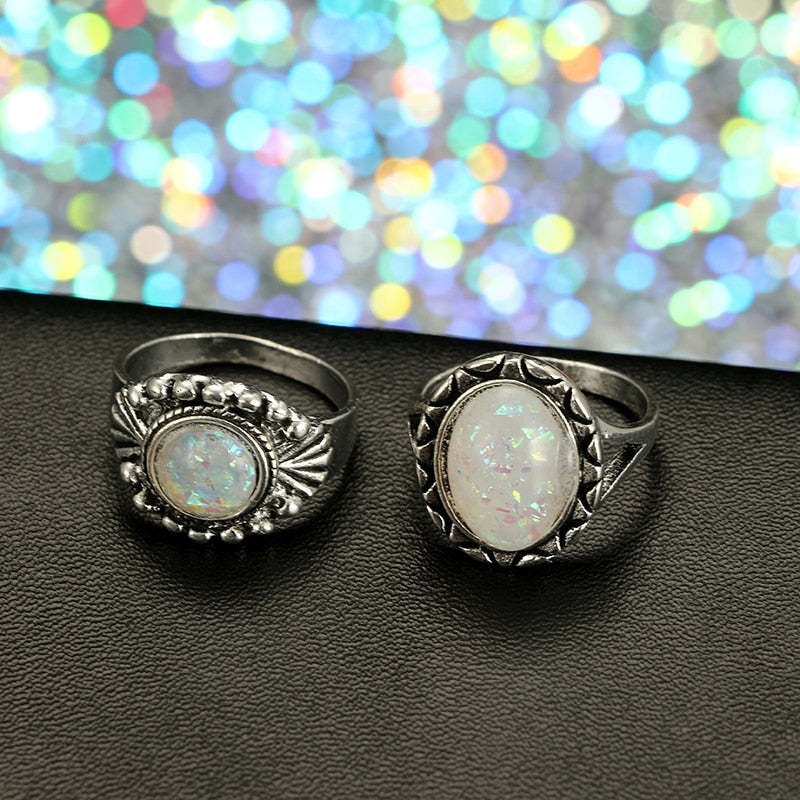 Eight-piece silver-tone opal-effect ring set with a close view of two decorated rings.