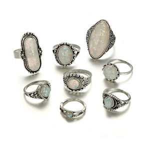 Eight-piece silver-tone opal-effect ring set shown together in a second arrangement on white.