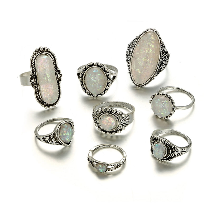 Eight-piece silver-tone opal-effect ring set shown together in a second arrangement on white.