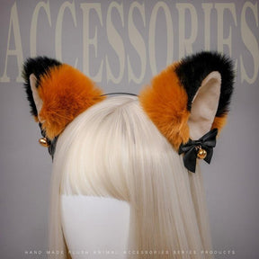 Fuzzy orange and black cat ear headband with pale inner ears, black ribbon bows, and gold-tone bells