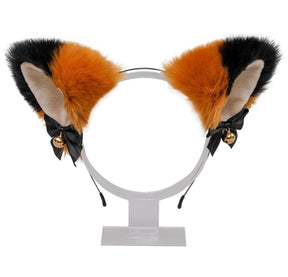 Fuzzy orange and black cat ear headband with pale inner ears, black ribbon bows, and gold-tone bells